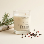 A Call Meets Mych 'birch + peppercorn 13210' scented candle in a clear glass jar with white wax, set against a plain white background.