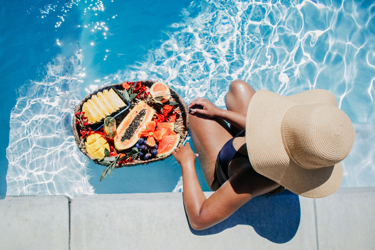 Women in a pool with a tropical fruit spread. 
